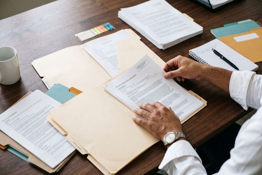 An advocate sorting a client's medical records across labelled folders on a desk